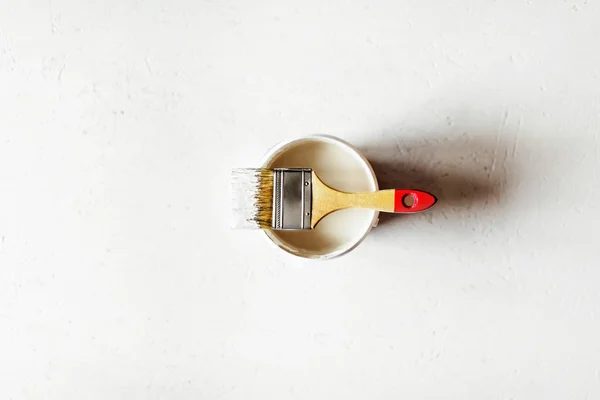 Construction brush with red handle on paint jar on painted plywood. — Stock Photo, Image