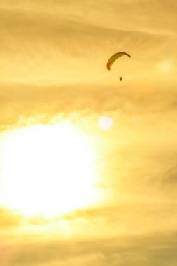bulutların üzerinde uçan yamaç paraşütçüleri pilotu ile gün batımı