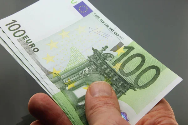 Stack of euros money in hand, hundred euro banknotes in cash on dark background, many twenty euro banknotes