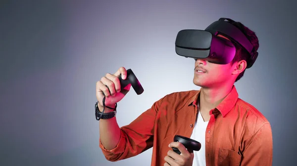 başka bir dünyayı keşfetmek VR gözlük ve iki gamepad mücadele kullanan adam
