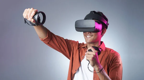başka bir dünyayı keşfetmek VR gözlük ve iki gamepad mücadele kullanan adam