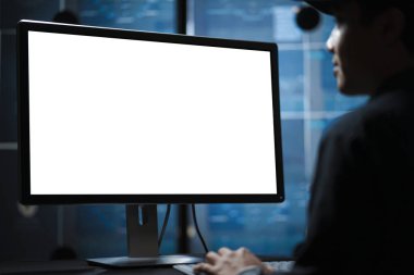 young man working on a blank screen in a dark room office clipart