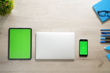 dijital tablet ve kroma anahtar yeşil ekranlı akıllı telefon ile beyaz dizüstü bilgisayar. Ahşap masa üzerinde izole ekranlı tüm.