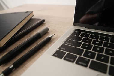 Boş ekranlı dizüstü bilgisayarı, siyah dizüstü bilgisayarları ve kalemleri açın. Ahşap masa üzerinde izole ekranlı tüm.