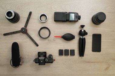 Hepsi bir kamera, lens, flaş, şimşek, pil, tripod, mikrofon ve ahşap masa üzerinde temizleyici