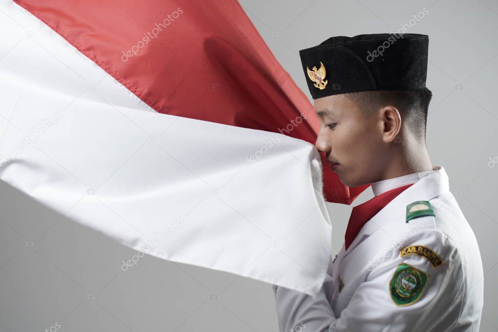 Close up young man Indonesian National Flag Hoisting Troop kissing the flag. National Paskibraka Council.