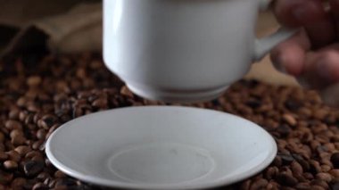 eller beyaz bir tabak üzerinde bir fincan kahve koymak