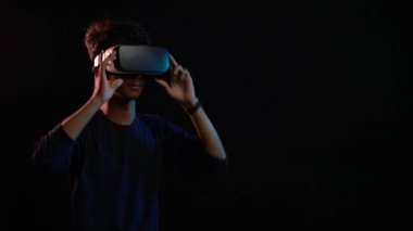 Siyah arka planda izole edilmiş sanal gerçeklik kulaklığı kullanan genç adam
