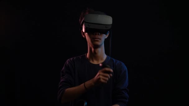 年轻人用虚拟现实耳机玩基于黑色背景的视频游戏 — 图库视频影像