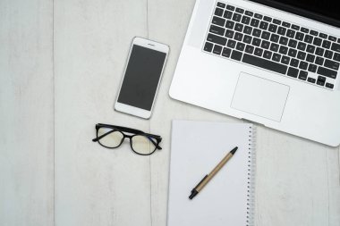 Dizüstü bilgisayarı, akıllı telefonu ve malzemeleri olan ahşap çalışma masası..