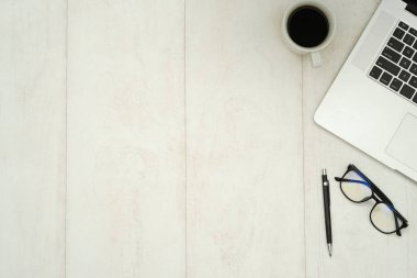 Dizüstü bilgisayarı, akıllı telefonu ve malzemeleri olan ahşap çalışma masası..