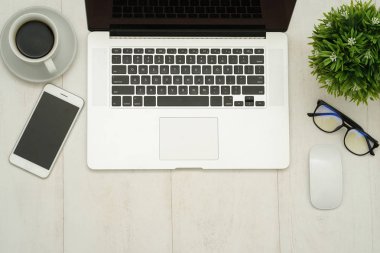 Dizüstü bilgisayarı, akıllı telefonu ve malzemeleri olan ahşap çalışma masası..