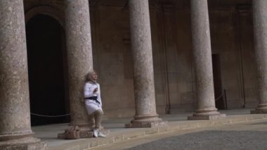 Bej çizgili genç bir kadın Charles V sarayının avlusunda Colonnade 'ın inşaat direğine yaslandı. Alhambra Sitesi. Granada, Endülüs, İspanya