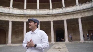Gülümseyen genç Asyalı adam Charles V sarayının avlusundaki Colonnade 'ın güzelliğine hayret etti. Alhambra Sitesi. Granada, Endülüs, İspanya