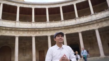 Gülümseyen genç Asyalı adam Charles V sarayının avlusundaki Colonnade 'ın güzelliğine hayret etti. Alhambra Sitesi. Granada, Endülüs, İspanya