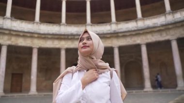 Bej eşarp takan Asyalı Müslüman bir kadın Charles V sarayının avlusundaki Colonnade 'ın güzelliğine hayret etti. Alhambra Sitesi. Granada, Endülüs, İspanya
