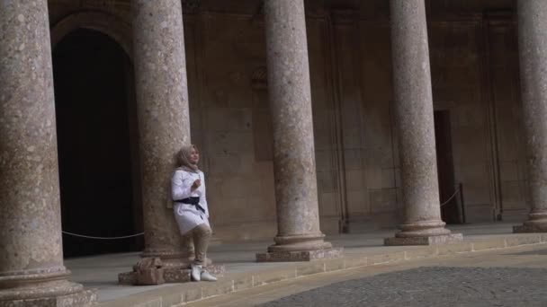 在查理五世宫殿的院子里 一位身穿米色雪弗衫的年轻女子靠在了一个柱顶上 Alhambra站点 格拉纳达 安达卢西亚 西班牙 — 图库视频影像