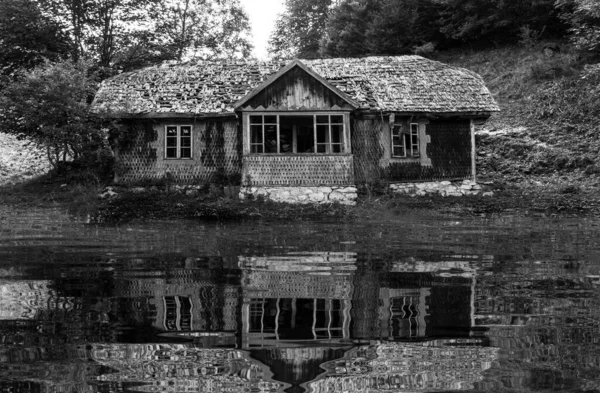 The dilapidated house on the waterfront. Abandoned house. Water reflection. Lake. Swamp