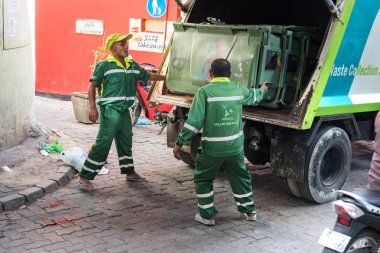Male, Maldivler-11 Şubat, 2019: Male, Maldivler 'de bir kamyonda çöp kutusu yükleyen Iki çöp toplayıcısı.