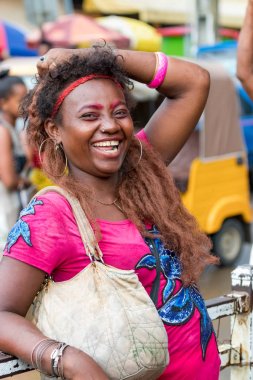 Nosy Be, Madagaskar-17 Ocak, 2019: renkli kıyafet kamera bakarak gülüyor ile yerel bir Madagaskar kadın, Nosy Be, Madagaskar ticari merkezinde korkuluk üzerinde eğilme.