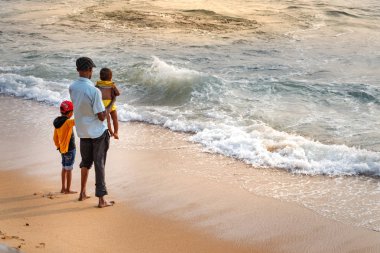 Colombo, Sri Lanka-19 Şubat 2019: Colombo, Sri Lanka 'daki Galleface plajında çocukları ile denize bakan bir baba.