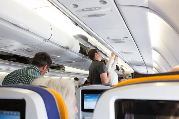 Passageiros que levam a bagagem do compartimento aéreo . — Fotografia de Stock