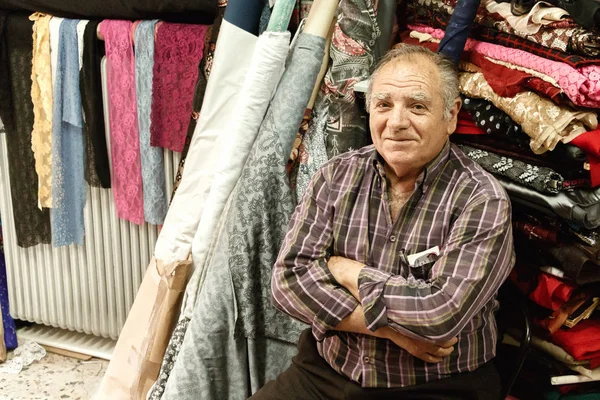 Portrét staršího muže z jeho obchodu s tkanina, Larissa, Řecko. — Stock fotografie