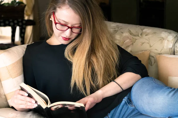 Портрет блондинки, читающей книгу в очках — стоковое фото