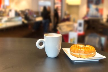 Kahveli bir kupa ve masada sandviç.