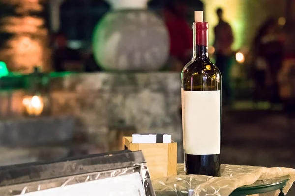 A wine bottle with a blank label on a table at the entrance of a Greek restaurant in Rhodes, Greece.