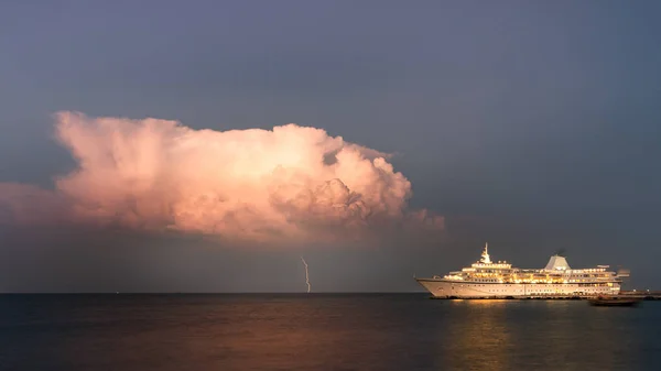 Un rayo golpeó el mar desde una nube tormentosa junto a un crucero atracado . — Foto de Stock