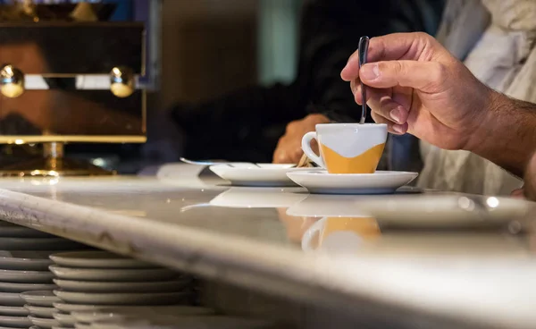Bir barda oturan bir espresso kahve fincanı karıştırarak bir erkek el.