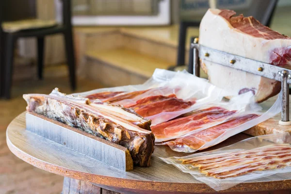 Houten tafel met rauwe ham in plakjes met ham in de rug — Stockfoto