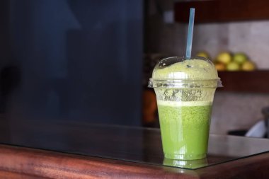 Saman ile plastik bir bardak üzerinde Yeşil sebze suyu.