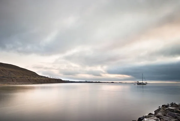 Paesaggio tranquillo con una barca a vela e una montagna con vecchie torri delle funivie nel porto di Longyearbyen . — Foto Stock