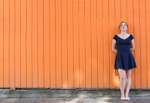 Young woman standing on a wall thinking.