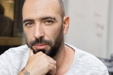 Sakallı ve kısa vızıltı saç kesim görünümlü kamera, ciddi, dalgın bir adam portresi.