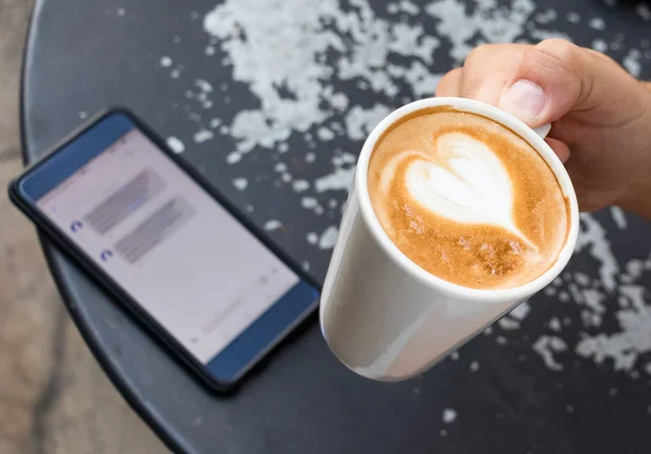 A male hand holding a cup of coffee, outdoors. — Stock Photo, Image