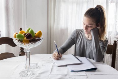 Evde ev ödevi yapan bir kız ortaokul öğrencisi.