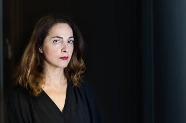 48 yaşında, ciddi, dalgın, siyah üzerine izole edilmiş bir kadının portresi.