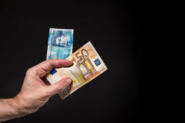 Beş pound ve 50 (elli) Euro banknotlar tutan bir erkek el, brexit kavramı, siyah üzerinde izole.