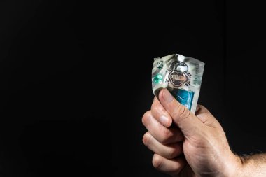 Yumruğunda beş poundluk banknot tutan bir erkek el, siyah ın üzerinde izole edilmiş..