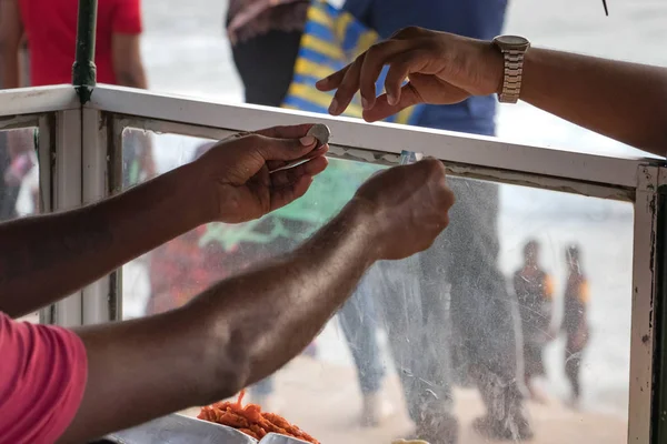 A street food vendor giving the change with coins to a customer at the street market in Galle Face st in Colombo, Sri Lanka.