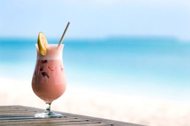 Maldivler'de bir plaj arka plan üzerinde üst ve saman bir dilim muz ile bir kokteyl cam İçecek meyve yüzlü.