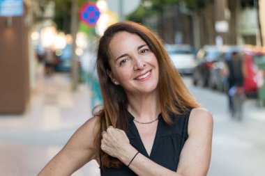 Olgun bir kadının portresi, 40s, gülümseyen görünümlü kamera açık havada.