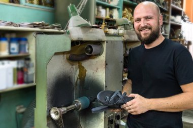Bir erkek ayakkabıcı yanında taşlama poz, kum bir çift tutan