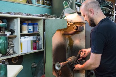 Bir erkek ayakkabıcı taşlama ve atölyesinde bir sandalet şekillendirme.