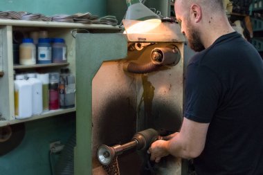 Bir erkek ayakkabıcı taşlama ve atölyesinde bir sandalet şekillendirme.