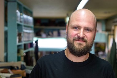 Sakallı kel bir mand portresi, ayakkabıcı onun atölyesinde kamera bakıyor.