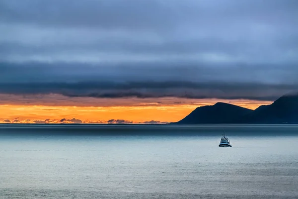 Fırtınalı bir günde alacakaranlıkta arka planda Bering denizi ve St Lawrence adasında küçük bir geminin manzarası, Alaska.